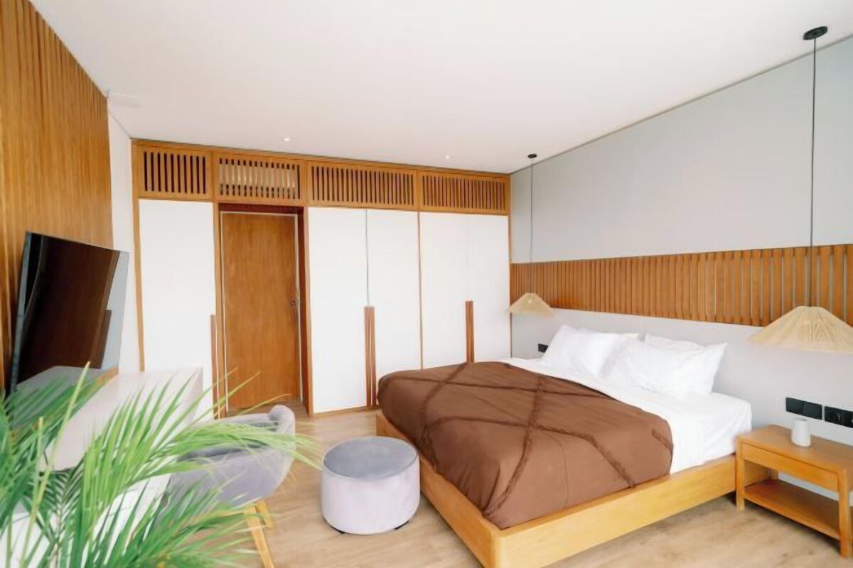 Un dormitorio moderno con cama, mesita de noche y televisor.