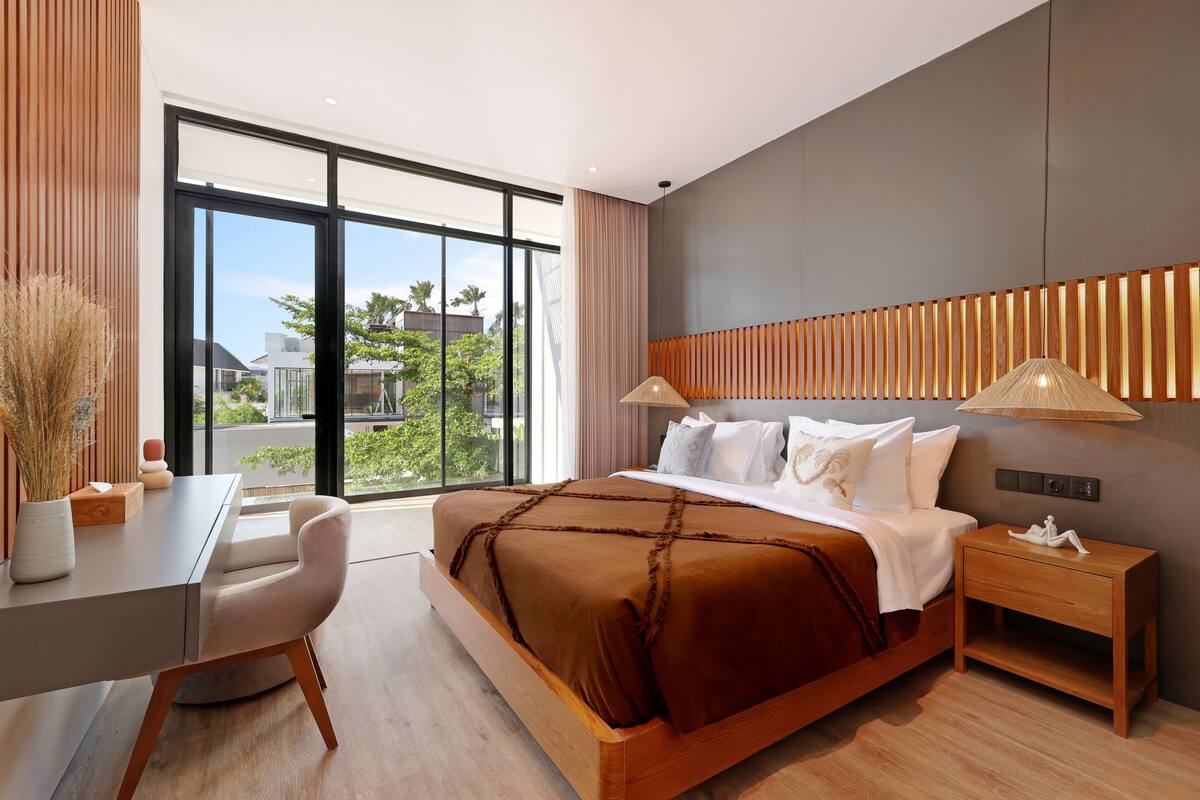 Habitación de hotel moderna con una cama grande, un escritorio y vistas al exterior.