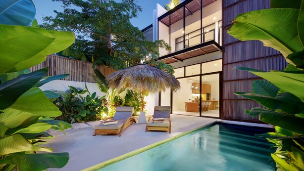 A modern house with a swimming pool, two lounge chairs, and a thatched umbrella. - Paradise Living Villa Canggu (Canggu)