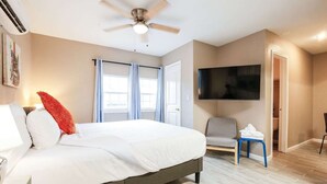 Ein Hotelzimmer mit Bett, Deckenventilator, Fernseher und Stuhl.