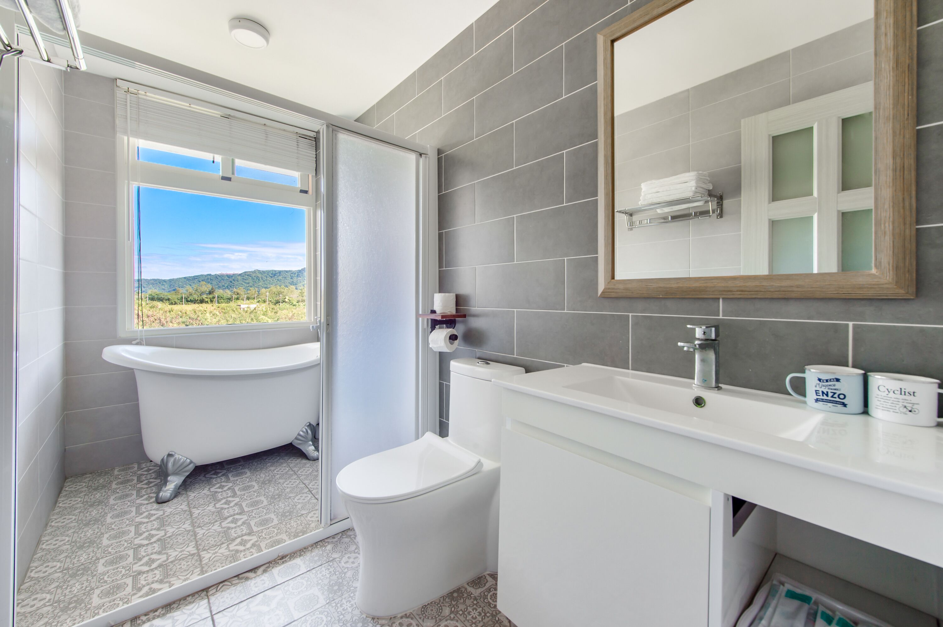 Un baño con bañera, inodoro y lavabo. Hay una ventana con vistas a zonas verdes.