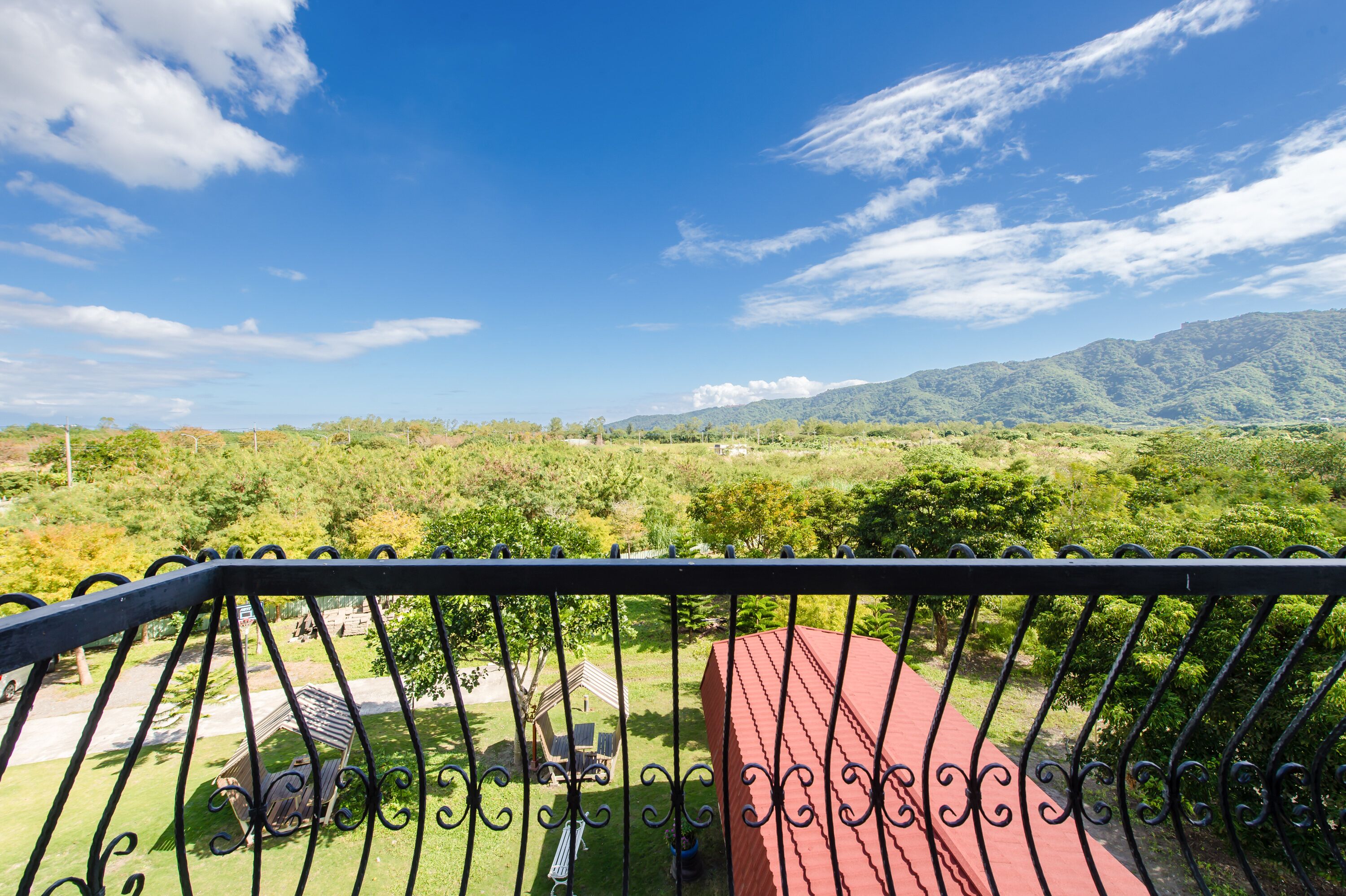 A balcony with a view of a lush green landscape and mountains in the distance.