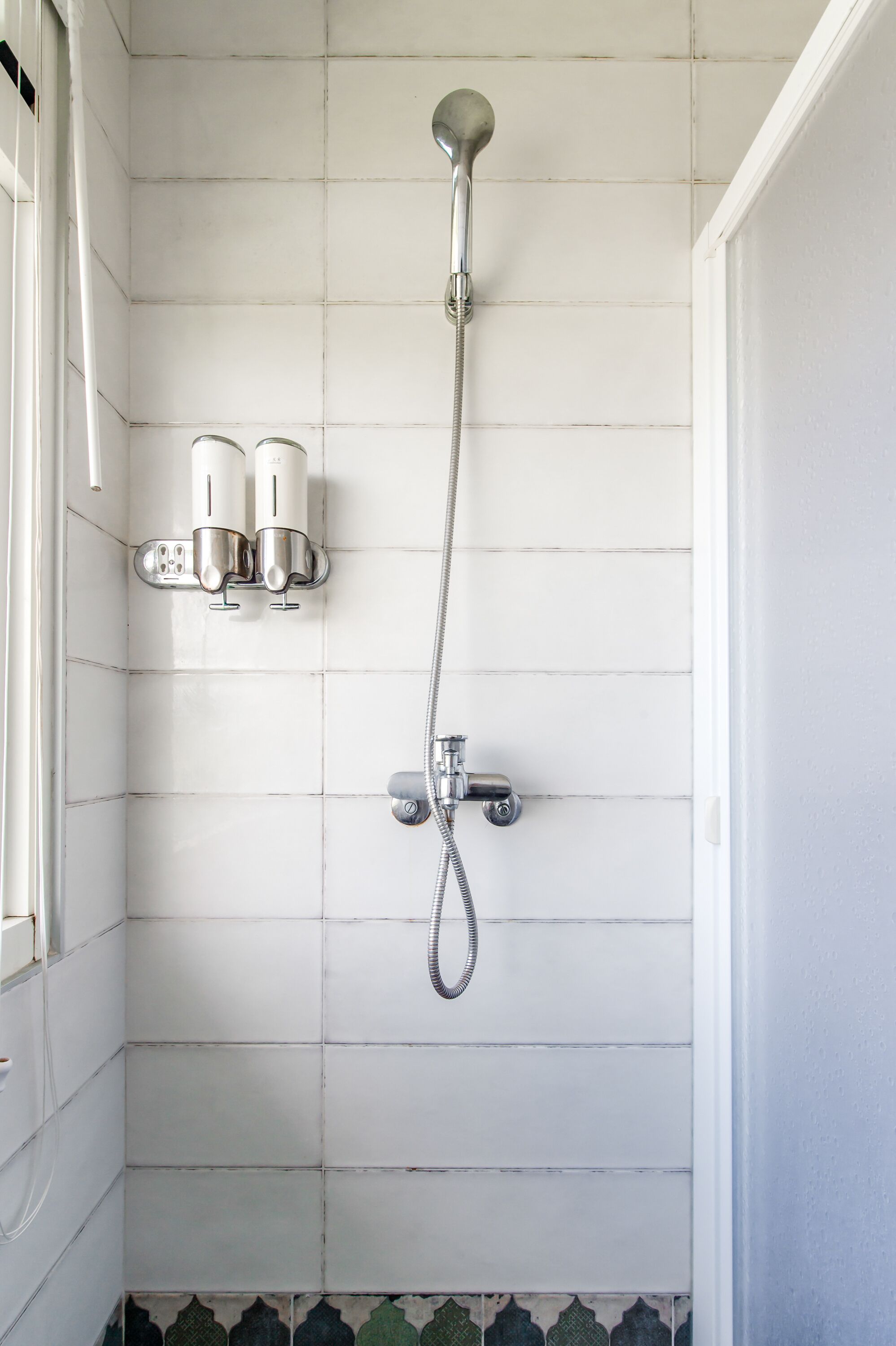 A shower with a handheld showerhead and a wall-mounted faucet.