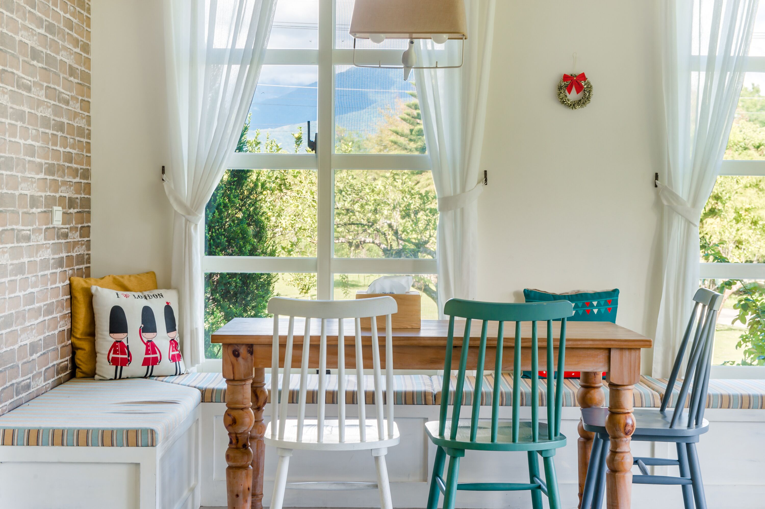 Un rincón acogedor con un banco y sillas de madera, una mesita y vistas a zonas verdes.