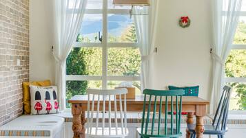 Un rincón acogedor con un banco y sillas de madera, una mesita y vistas a zonas verdes.