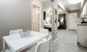 Habitación de hotel compacta con área de comedor, kitchenette y baño con ducha e inodoro.