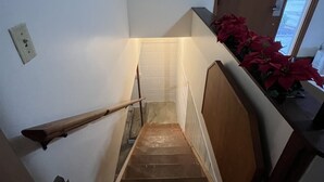 A wooden staircase with a handrail, a white wall, and a door leading to a room with a view. - Spacious three bedroom home located 5 minutes from WEC  (Wilmington)