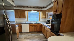 A kitchen with wooden cabinets, a stainless steel refrigerator, a dishwasher, a sink, and a window with blinds. - Spacious three bedroom home located 5 minutes from WEC  (Wilmington)