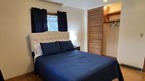 A bedroom with a large bed, a nightstand, a window with curtains, a wooden door, and a wall-mounted heater. - Spacious three bedroom home located 5 minutes from WEC  (Wilmington)