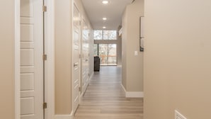 A hallway with a wooden floor, white doors, and a large window at the end. - Big Family Lake Retreat | 6BR Table Rock (Cape Fair)