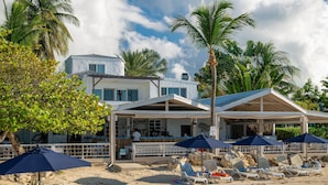 A beachfront property with a bar, lounge chairs, and umbrellas. - Romantic Antigua Getaway – Oceanfront Condo with Resort Amenities (Saint Johns)