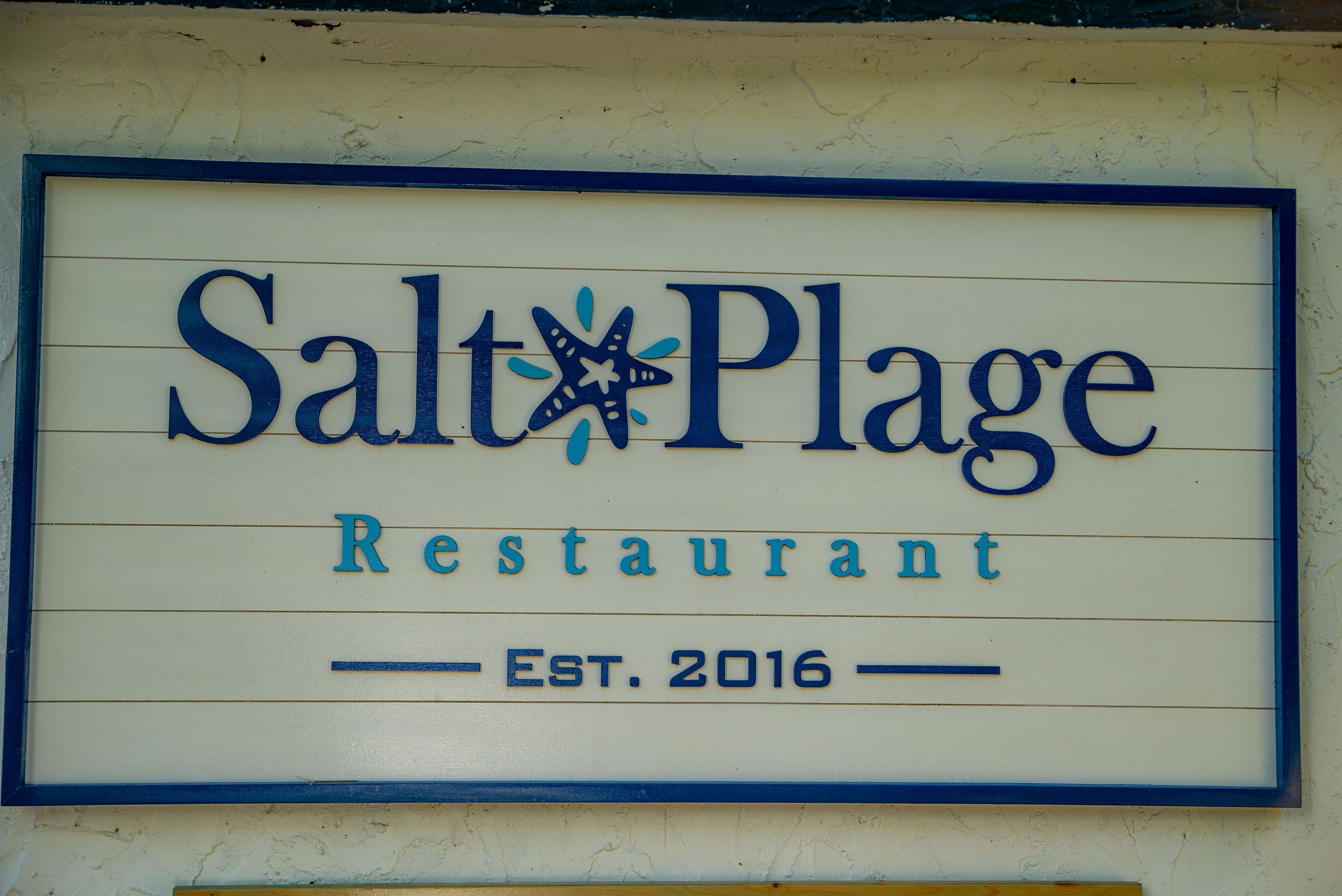 A sign for Salt Plage Restaurant with a star and the establishment year 2016.