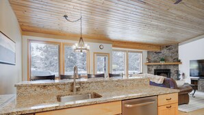 A spacious kitchen with granite countertops, wooden cabinets, and a stone fireplace.