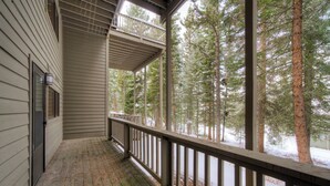 A wooden porch with a railing, overlooking a snowy forest.