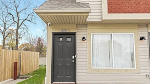 A house with a dark front door, a 'hello' mat, and a window with curtains. - Charming New Unit in the Heart of Roseville (Roseville)