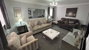 A living room with a sofa, armchair, coffee table, and a TV. - Spacious House To Accommodate 6 (Shavington)