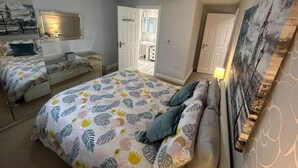 A bedroom with a bed, a dresser, a mirror, and a door leading to another room. - Spacious House To Accommodate 6 (Shavington)