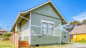 Eenlaags huis met een puntgevel, een veranda met treden en een kleine voortuin.