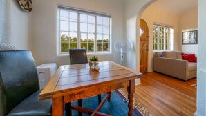 A cozy living room with a wooden dining table, a sofa, and a fan.