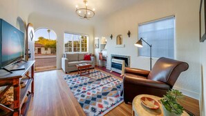 A living room with a television, sofa, coffee table, fireplace, and a patterned rug.