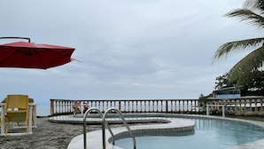 Ein Swimmingpool mit weißer Brüstung, einem roten Sonnenschirm und einem gelben Stuhl.