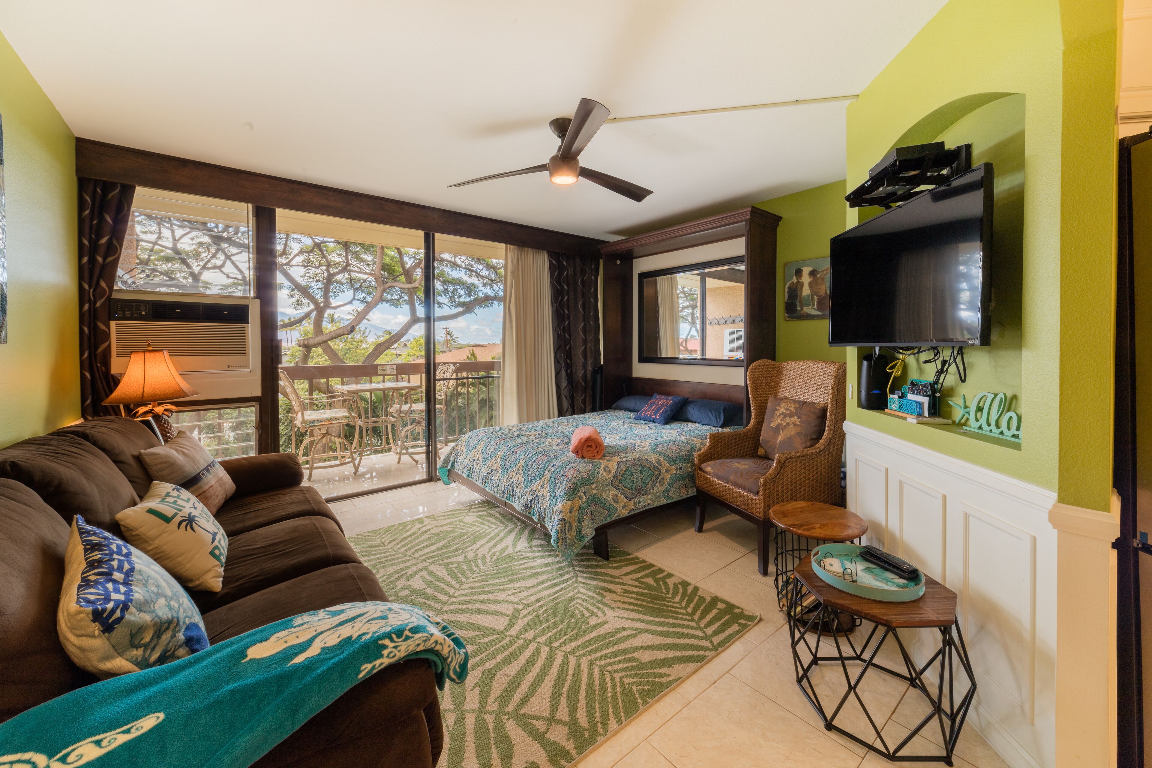 A room with a bed, a sofa, a chair, a small table, and a television.