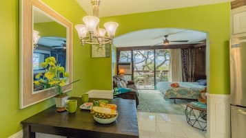 A bright green room with a dining area, a large mirror, and a view of the outdoors.