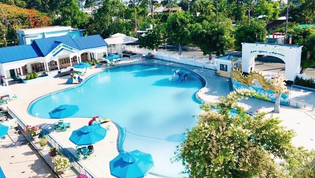 A large swimming pool with multiple lanes, surrounded by lounge areas with umbrellas and seating. - Cao Lanh Hotel (My Tho)