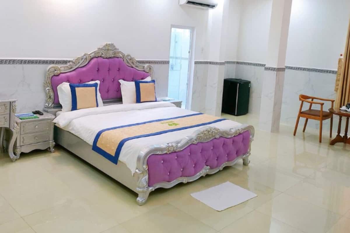 Une chambre avec un grand lit, une coiffeuse avec un miroir, une chaise et une valise.
