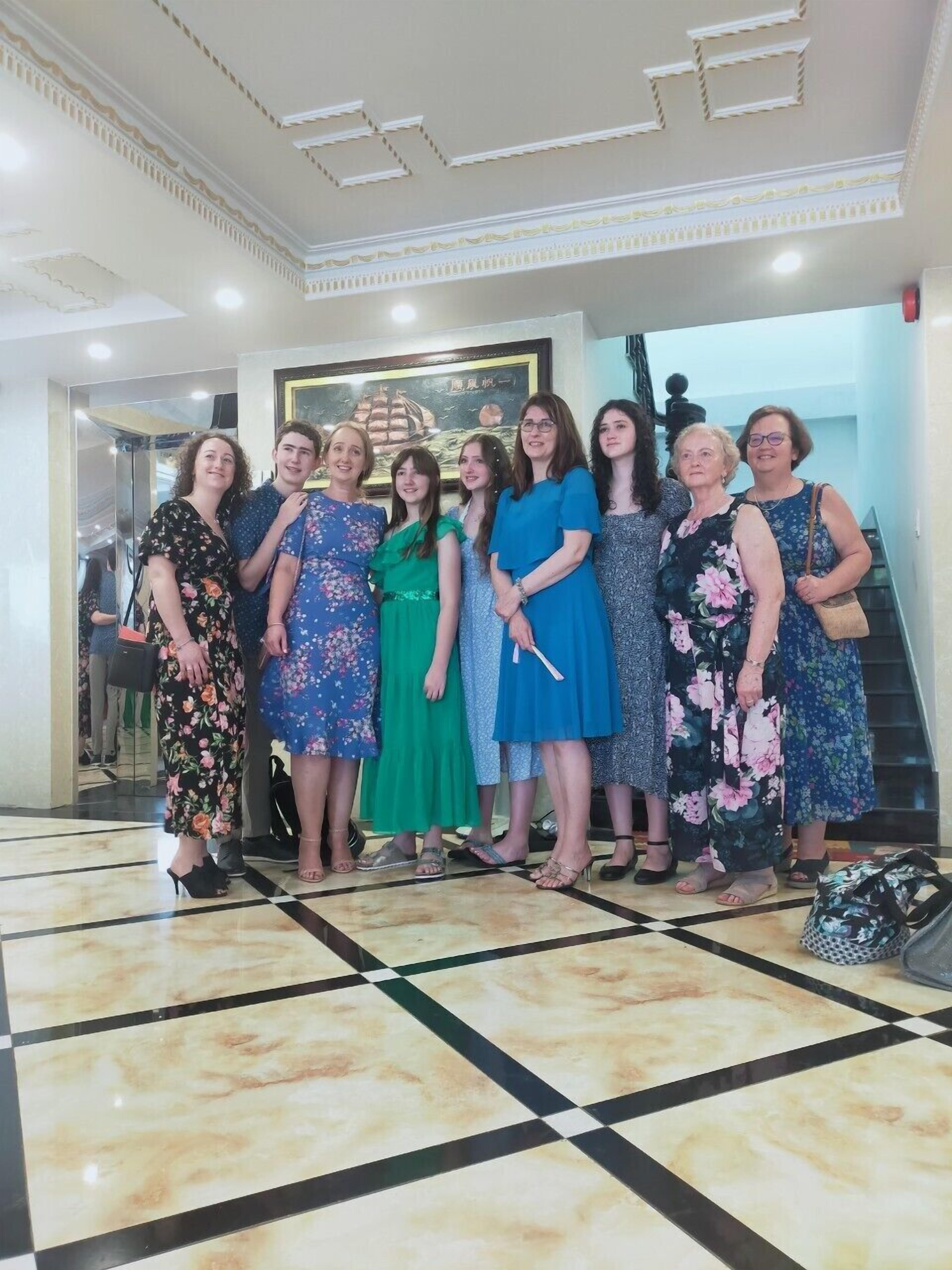 Un grupo de personas en un vestíbulo con piso a cuadros y un cuadro enmarcado en la pared.