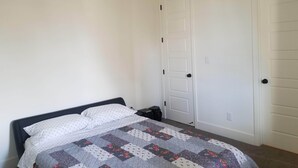 A bedroom with a bed, a ceiling fan, and a white door. - Private Guest Suite (Visalia)