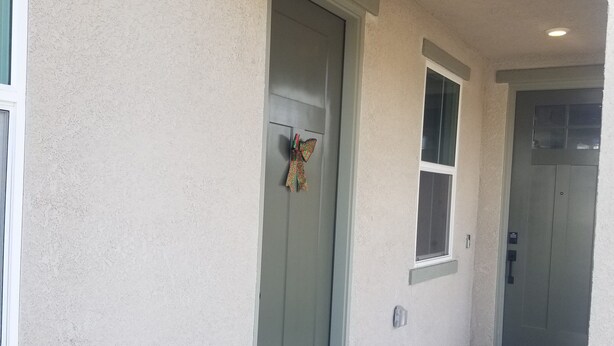 A building entrance with a green door, a butterfly decoration, and a small window above the door. - Private Guest Suite (Visalia)