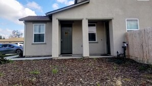 A two-story building with a front door, two windows on the ground floor, and a small porch area. - Private Guest Suite (Visalia)