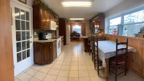 A kitchen with wooden cabinets, a dining table with chairs, and a view through a window. - BRAND NEW LISTING! 3BR/2BA Country Farmhouse Overlooking Little Tennessee River (Franklin)