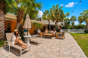 A patio area with outdoor seating, palm trees, and a white fence in the background. - Miami & Me Oasis: Dive into Beach Bliss, King Size Comfort, and Gulfside Glam! (Indian Rocks Beach)