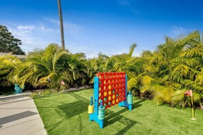 A colorful playground with a red and blue ball maze, surrounded by lush greenery and palm trees.