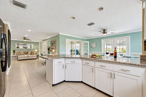 Una cocina moderna con armarios blancos, encimera de granito y comedor con sofá y mesa de centro.