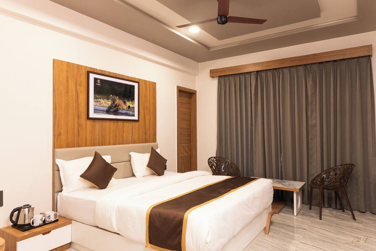 Ein Hotelzimmer mit einem Bett, einem Schreibtisch, zwei Stühlen, einer Kaffeemaschine und einem gerahmten Bild an der Wand.