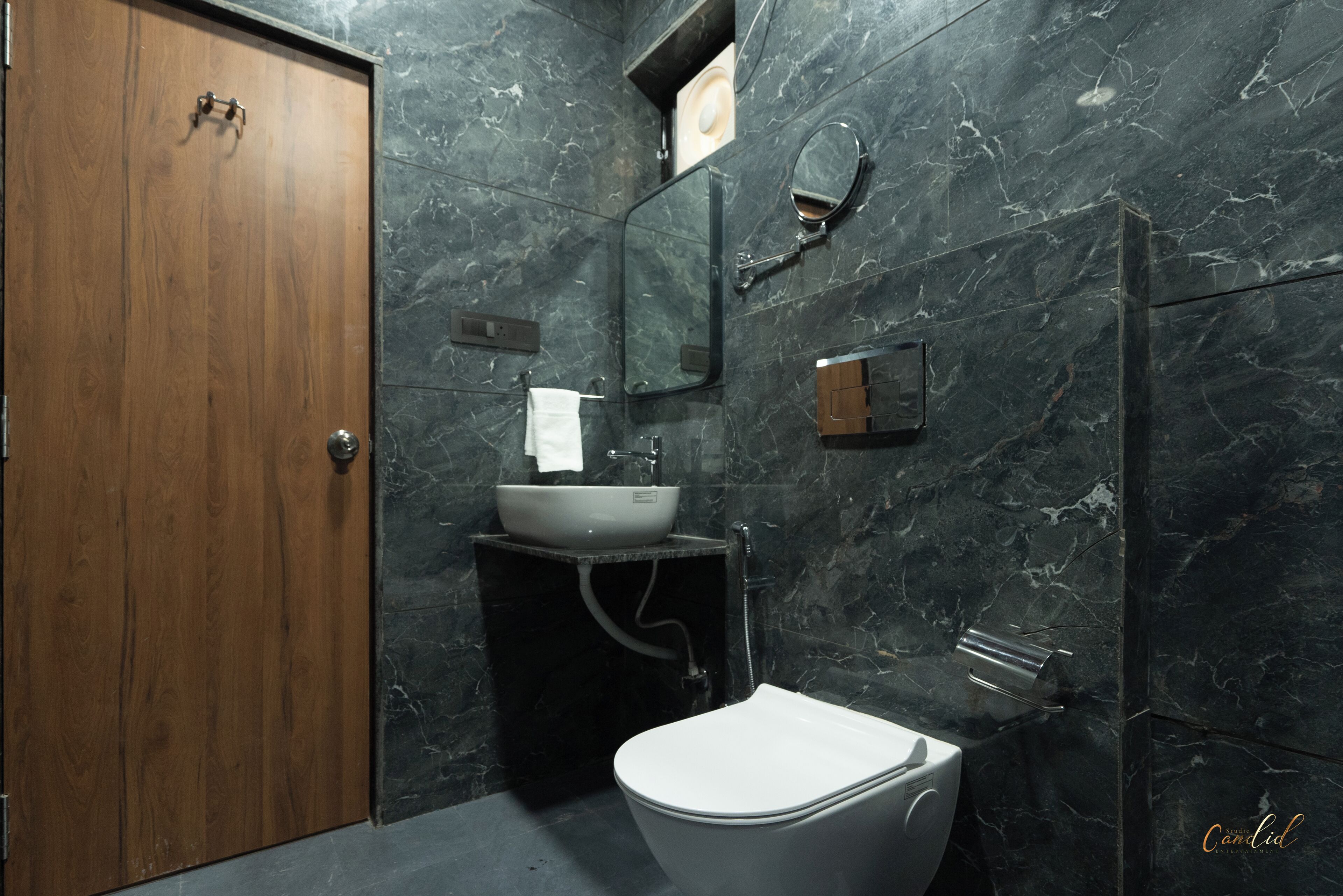 A bathroom with a wooden door, a white sink, a toilet, and a mirror.