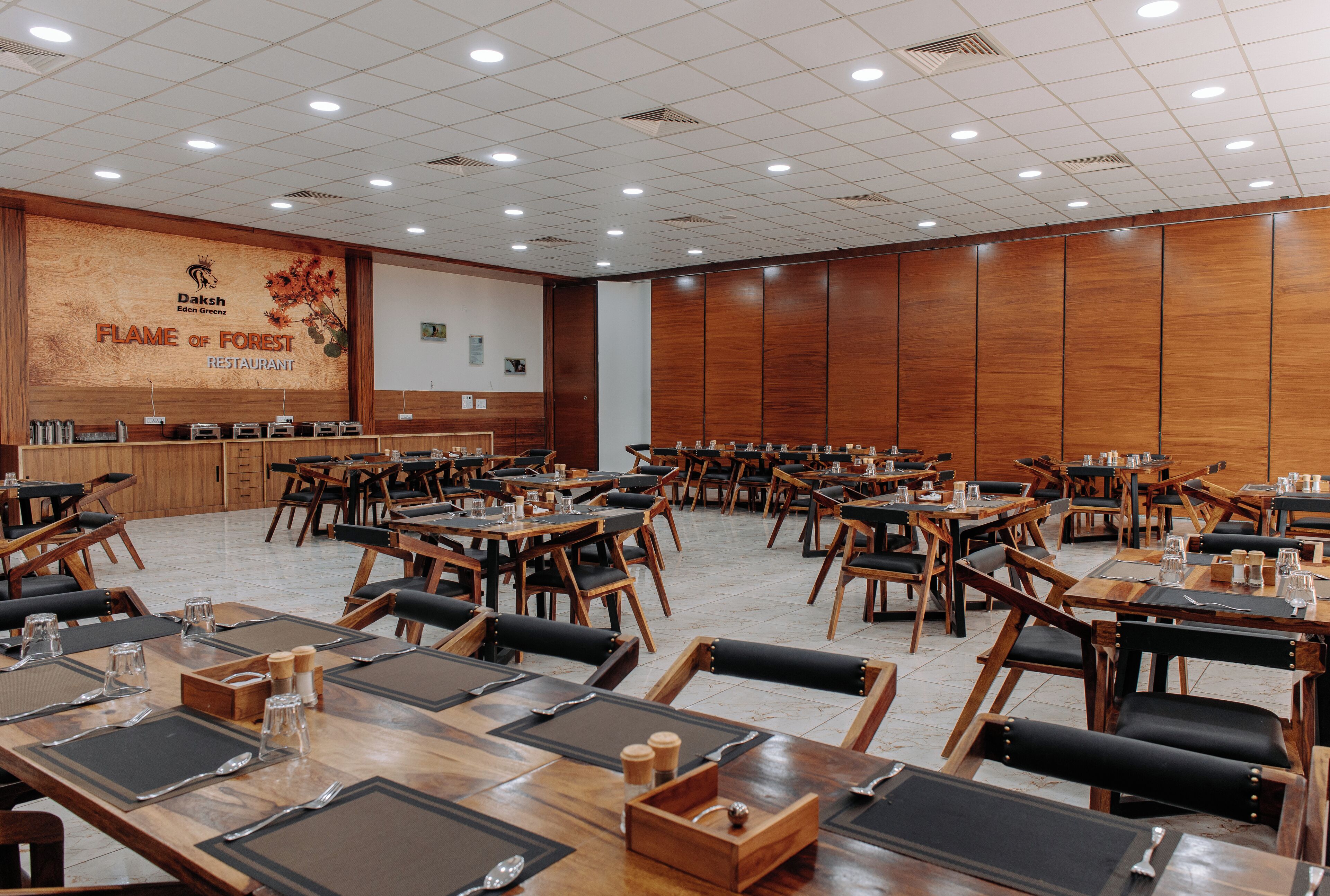 A conference room with multiple tables and chairs, a wooden panel wall, and a presentation screen.
