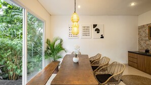 Un espace repas moderne avec une table en bois, des chaises en osier et un luminaire suspendu.