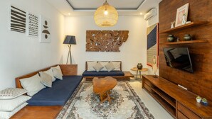 Un salon moderne comprenant un canapé, une table basse, un téléviseur et un élément décoratif mural.