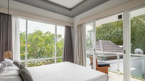Une chambre moderne avec un grand lit, une vue sur la verdure et un balcon avec une porte vitrée.