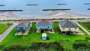 Uma área residencial costeira com três casas, um pequeno anexo e vista clara para o oceano.