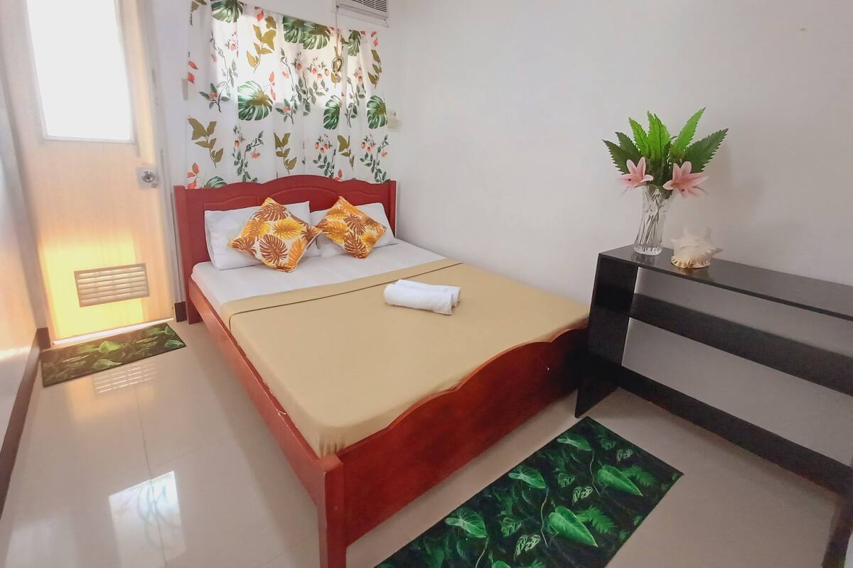 A neatly arranged bedroom with a bed, bedside table, and a small potted plant.