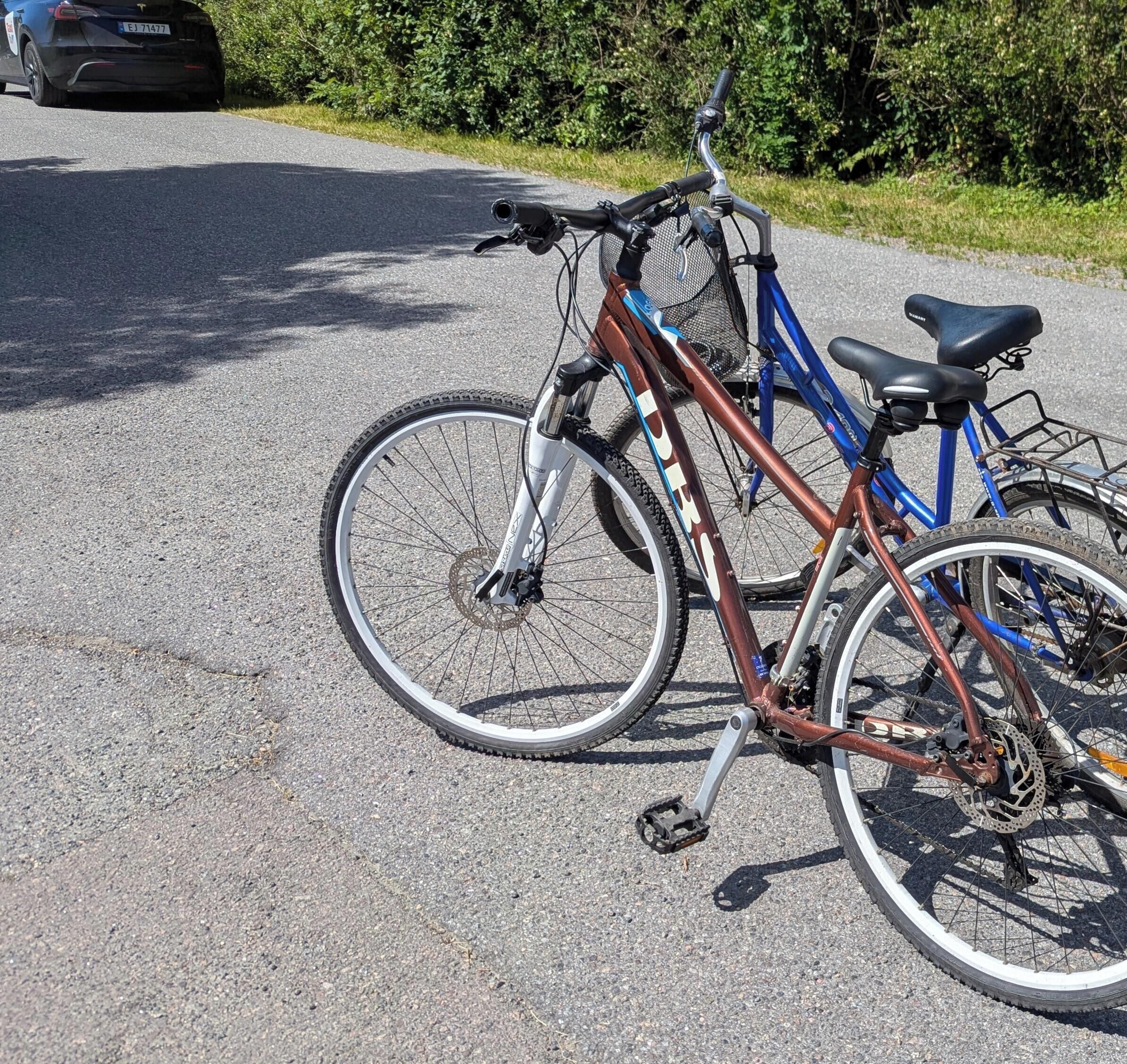 Un vélo est garé sur une surface pavée, avec une voiture en arrière-plan.