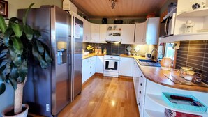 Una cocina moderna con electrodomésticos de acero inoxidable, piso de madera y muebles de color blanco.