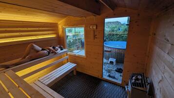 Relax in a serene sauna with a view of lush greenery, featuring a comfortable bench and a small heater.