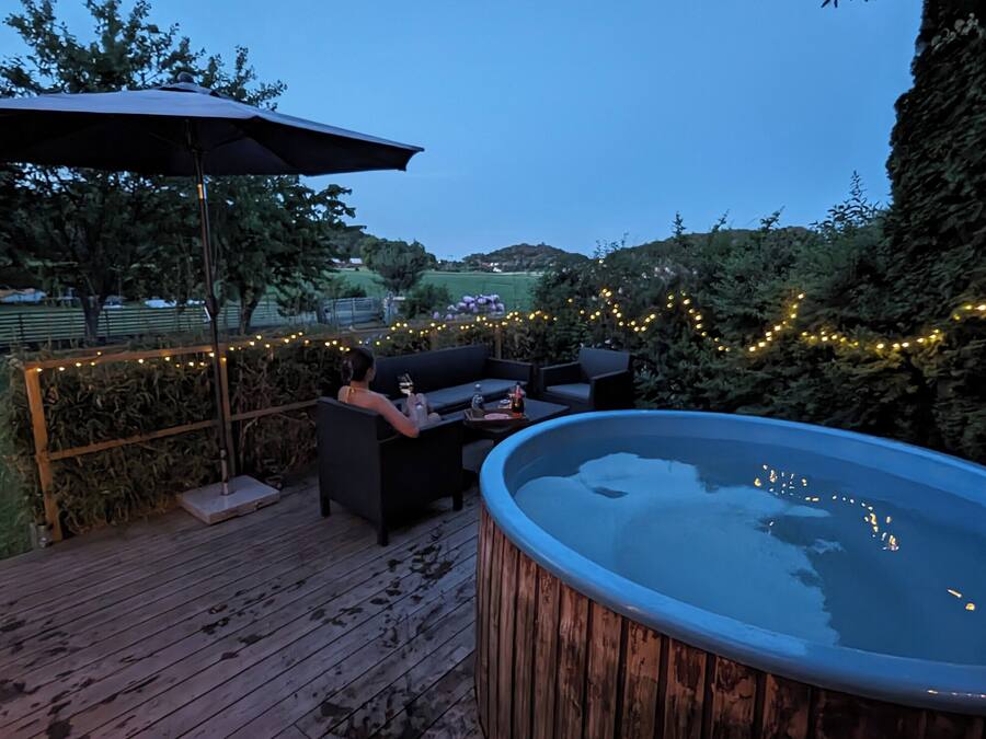 Eine Holzterrasse mit Whirlpool, Sitzgelegenheit und Lichterketten.
