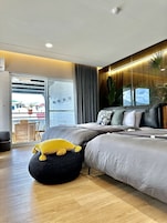 Quarto moderno com uma cama grande, um espaço de estar pequeno e vista para o exterior.